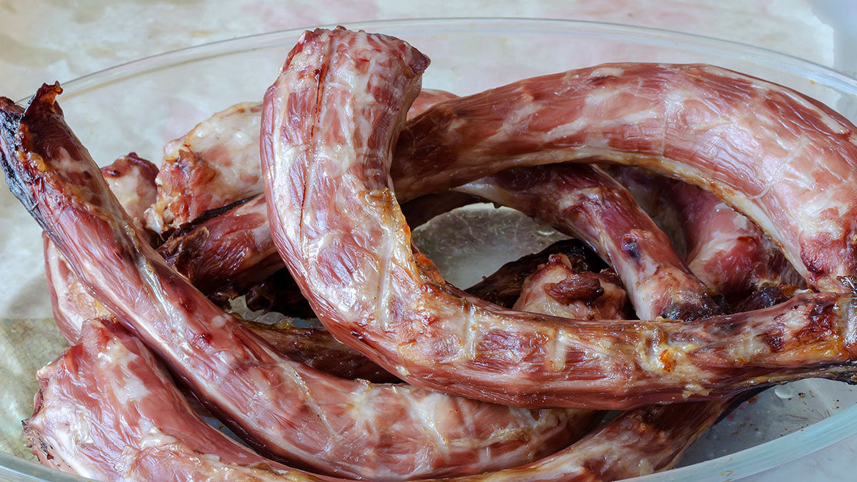 Can dogs eat turkey necks? Image of a glass bowl filled with raw turkey necks.