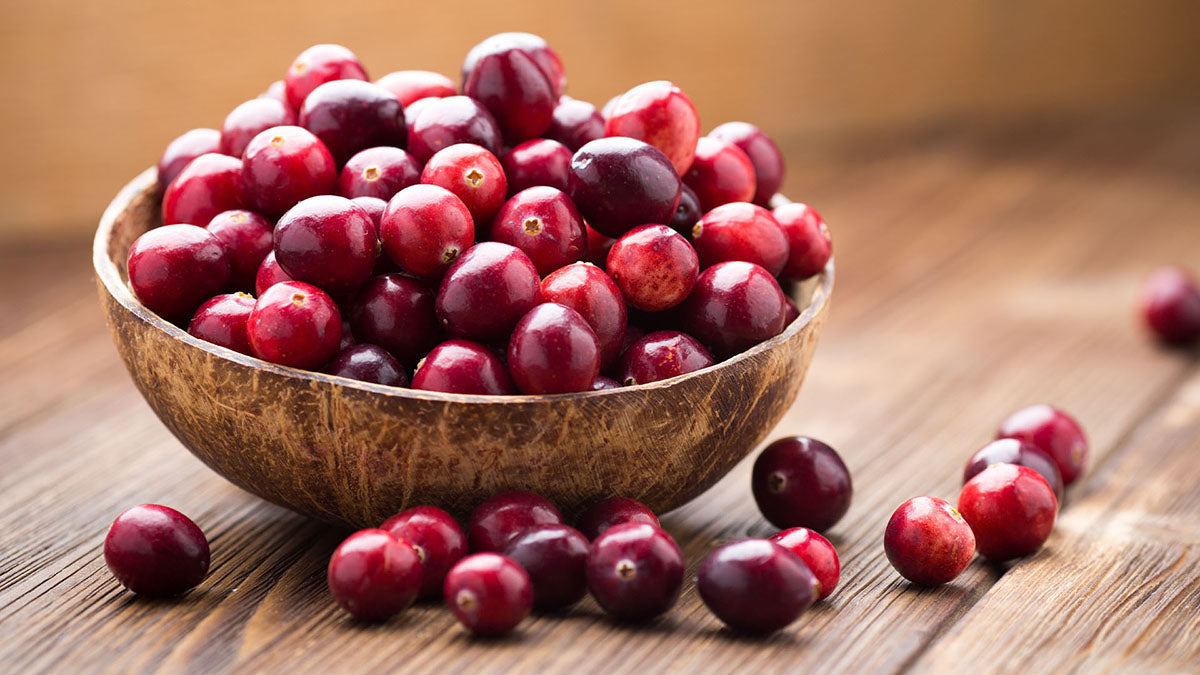Bowl of cranberries on a wooden surface. Cranberries can offer many benefits to dogs.